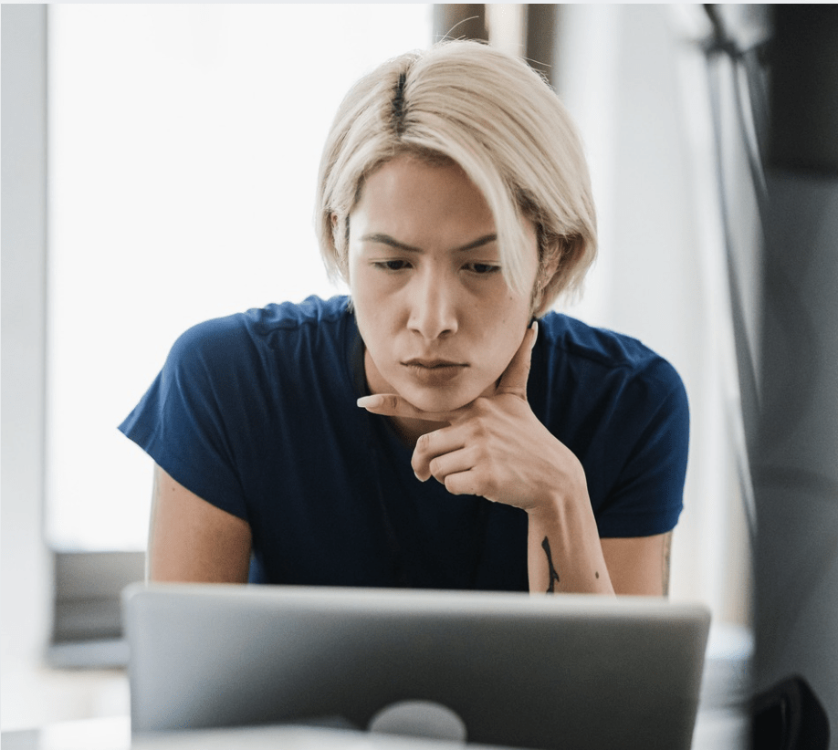 Person leaning over a laptop with a concerned, thoughtful expression while reviewing something online